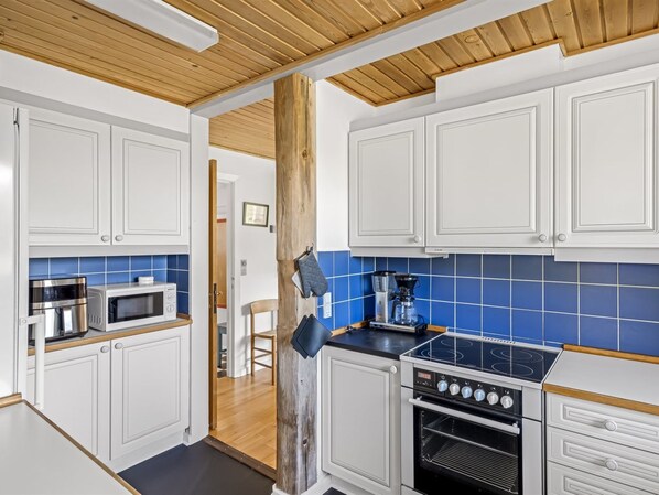 A modern kitchen with white cabinetry, a black stove, and a blue-tiled backsplash.