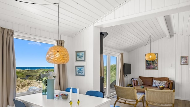 Una habitación con una mesa de comedor, sillas, un sofá y un televisor. Hay ventanas con vistas al exterior.