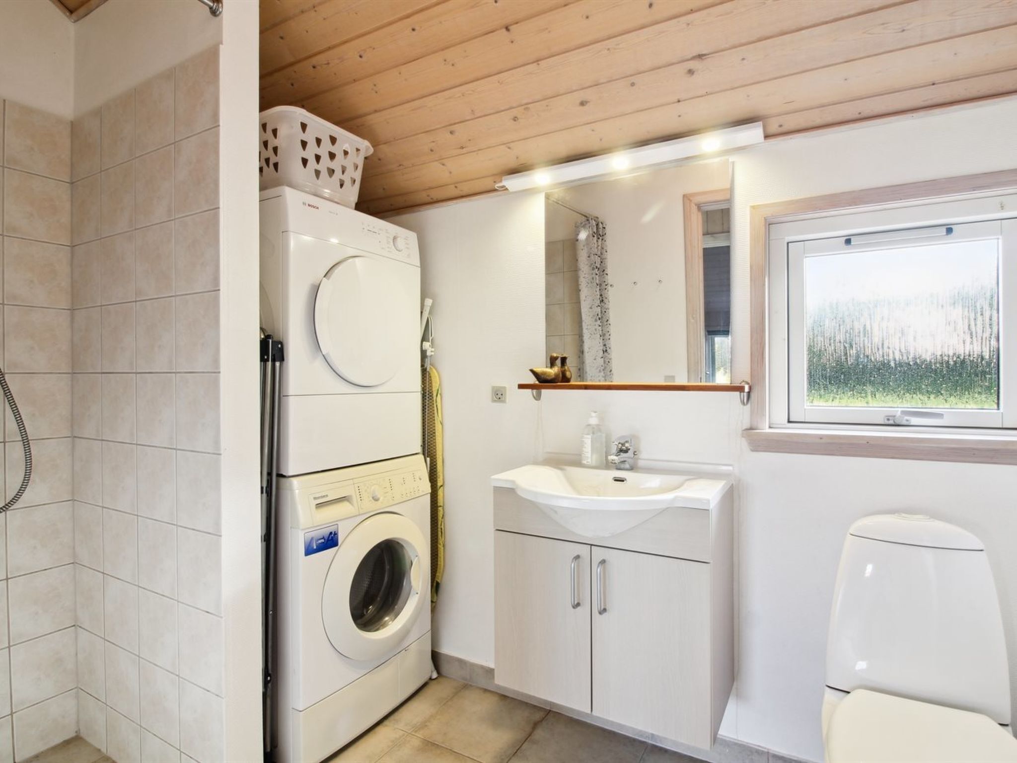 Une petite salle de bain équipée d’un lave-linge, d’un évier et de toilettes.