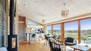 Ein modernes Interieur mit Küche, Essbereich und großen Fenstern mit Blick ins Freie.