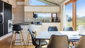 Eine moderne Küche mit integriertem Wasch- und Trockner, einem Essbereich mit Tisch und Stühlen sowie einem großen Fenster mit Blick ins Freie.