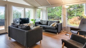A spacious living room with a large sofa, a smaller sofa, and a chair. There is a television on a wooden table, and a plant on the floor. - "Kragh" - 950m from the sea by Interhome (Løkken)