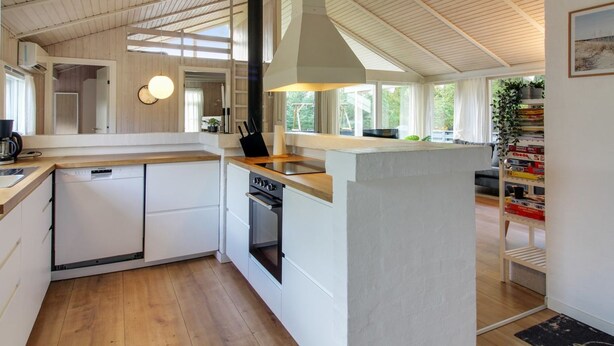A modern kitchen with white cabinetry, a central island, and a large window providing natural light. - "Kragh" - 950m from the sea by Interhome (Løkken)