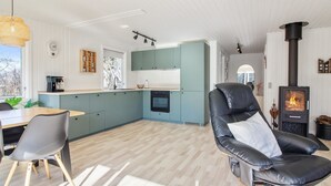 Moderni keittiö, jossa on turkoosinsiniset kaapit, musta liesi ja ruokailutila, jossa on nahkainen tuoli ja pöytä.