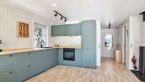 Moderni keittiö, jossa on vaaleansiniset kaapit, puinen työtaso ja sisäänrakennettu uuni.