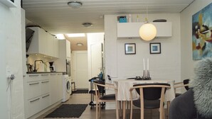 Una cocina moderna con armarios blancos, una lavadora y un comedor con mesa y sillas.