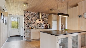 A modern kitchen with wooden ceiling, patterned backsplash, and a central island with glass-fronted cabinets. - "Letizia" - 700m from the sea by Interhome (Hals)