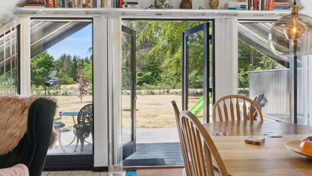 A modern interior with a dining area, bookshelves, and a view of the outdoors.