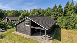 Une maison moderne avec un toit en pente, une véranda et un petit garage attenant.