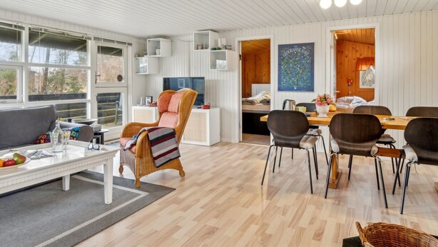 Un salon moderne et bien éclairé, comprenant un canapé, des fauteuils, une table à manger et un téléviseur.