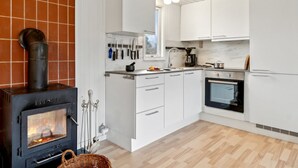 Une cuisine moderne avec des armoires blanches, un poêle à bois et un dosseret en marbre.