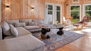 Une pièce aux murs lambrissés, avec un canapé, une table basse ronde et un fauteuil.