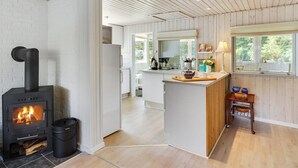 A modern kitchen with a wood-burning stove, white brick walls, and wooden ceiling beams. - "Rudi" - 450m from the sea by Interhome (Hals)