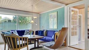 A modern living room with a blue sofa, wooden chairs, a coffee table, and a large window. - "Rudi" - 450m from the sea by Interhome (Hals)