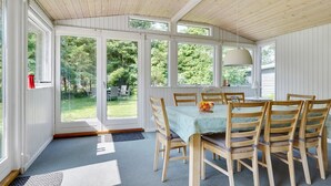 A dining area with a table set for four, surrounded by wooden chairs, large windows, and a ceiling with wooden beams. - "Rudi" - 450m from the sea by Interhome (Hals)