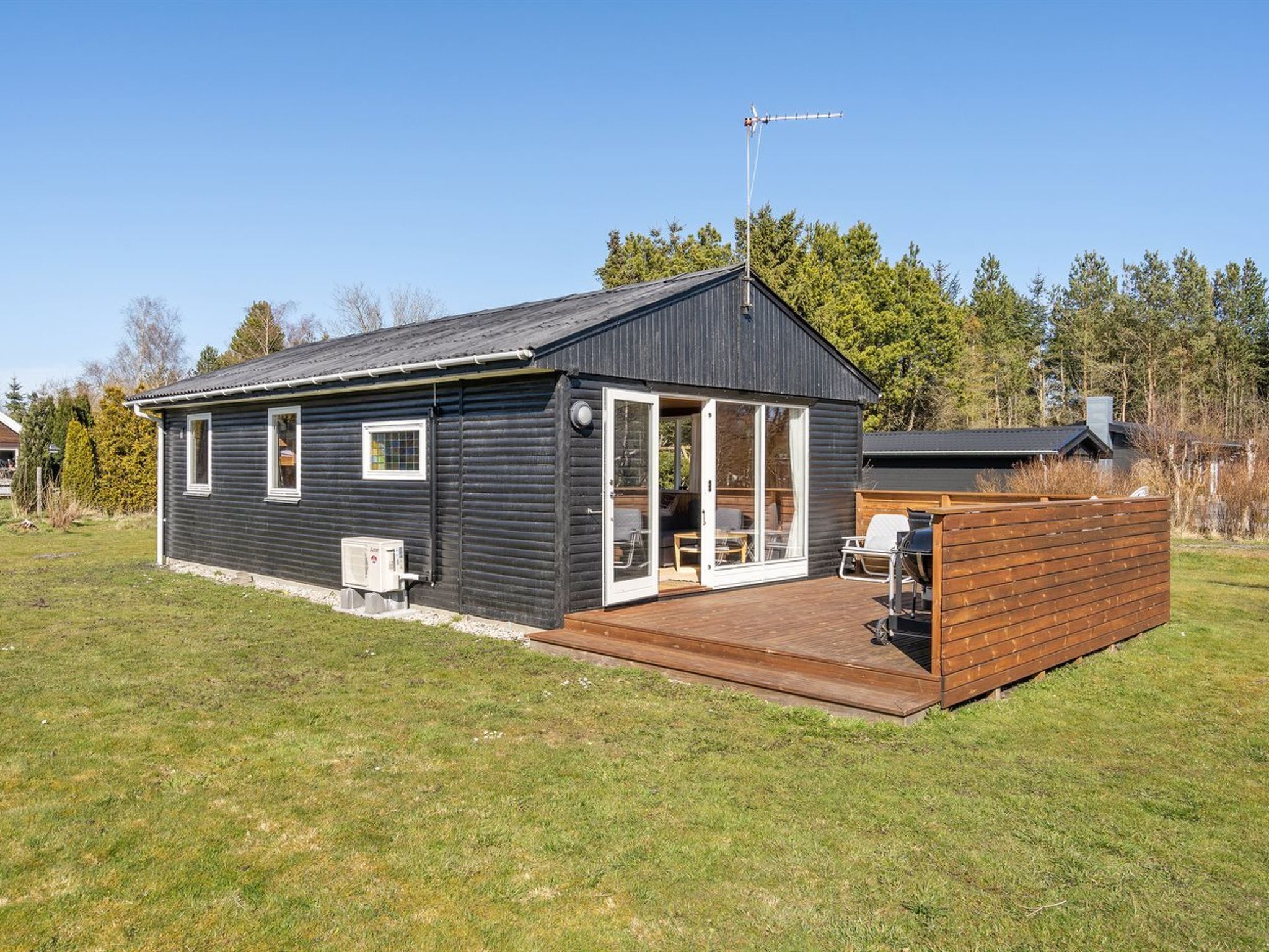 Ein eingeschossiges Blockhaus mit einer Terrasse, einer Satellitenschüssel und einem großen Fenster.