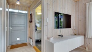Une salle de bain moderne avec un mur recouvert de panneaux en bois, un meuble-lavabo blanc et un grand miroir.