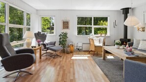 Ein geräumiges Wohnzimmer mit Kamin, großen Fenstern und einer gemütlichen Sitzecke.