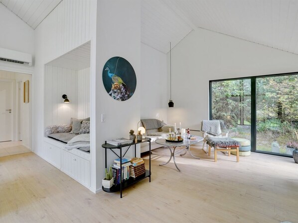 A modern living room with a large window, a round painting, and a cozy seating area.