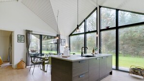 Eine moderne Küche mit großen Fenstern, einem Essbereich und Blick ins Freie.