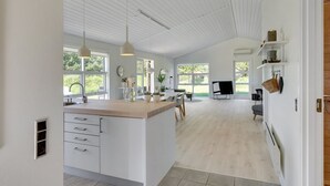 Een ruime keuken met een centraal kookeiland, grote ramen en een modern design.