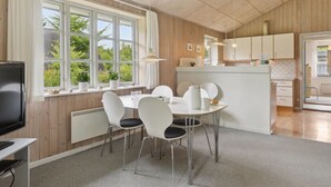 A modern kitchen with white cabinets and a dining area with a round table and white chairs. - "Henny" - 1.5km from the sea by Interhome (Hals)