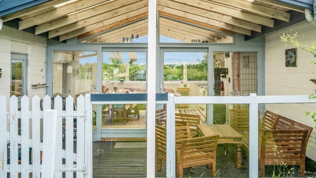 A covered outdoor seating area with wooden furniture and a white picket fence. - "Lenard" - 400m from the sea by Interhome (Hals)