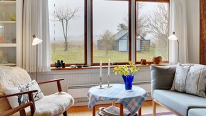 A cozy living room with a large window, a blue table with candles and flowers, a sofa, and a chair. - "Lenard" - 400m from the sea by Interhome (Hals)