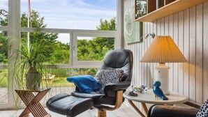Ein modernes Wohnzimmer mit einem schwarzen Ledersessel, einem blauen Hocker und einem Couchtisch aus Holz.