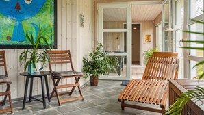 Ein Zimmer mit Holzwänden, einem großen Fenster, einer Holzbank und zwei Stühlen.