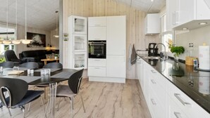 Eine moderne Küche mit weißen Schränken, einer schwarzen Arbeitsplatte und einem Essbereich mit Tisch und Stühlen.