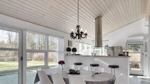 Une cuisine moderne dotée d’un îlot central, de grandes fenêtres et d’un lustre.