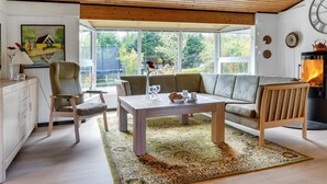 A modern living room with a wooden ceiling, a sofa, a dining table, and a fireplace.