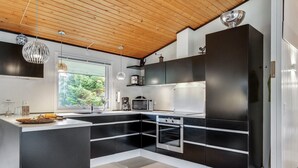 A modern kitchen with black and white cabinetry, a large island, and a wooden ceiling.