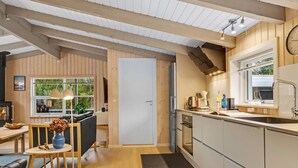 A modern kitchen with wooden cabinets, a built-in oven, and a window overlooking greenery.