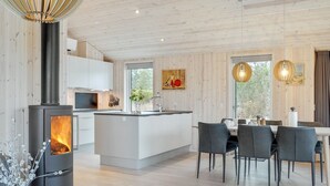 Een moderne keuken met een centraal eiland, een ingebouwde kookplaat en een eethoek met tafel en stoelen.