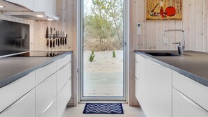 Een moderne keuken met een centraal eiland, een spoelbak en een deur naar een buitenruimte.