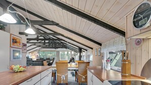Een moderne keuken met houten balken, een fornuis en een eethoek met rieten stoelen.