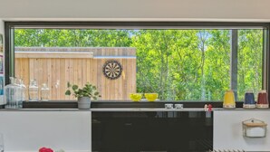 Et køkken med et stort vindue, en dartskive og diverse køkkenartikler på bordet.