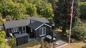 Et toetagers hus med mørk facade, en overdækket terrasse og et flagstang.