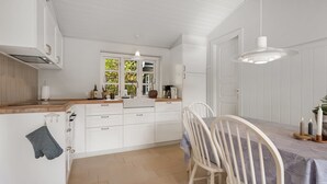 Et moderne køkken med hvide skabe, en træbordplade og et spiseområde med et bord og stole.