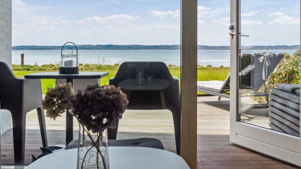 Une pièce avec vue sur un lac, une table avec une bougie et une chaise.