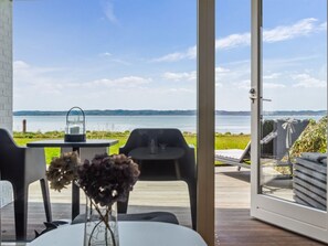 Een kamer met uitzicht op een meer, een tafel met een kaars en een stoel.