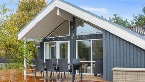 A modern house with a covered patio, a dining area with outdoor furniture, and a large window. - "Etel" - 600m from the sea by Interhome (Ebeltoft)