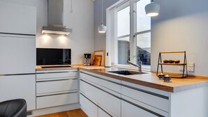 Una cocina moderna con armarios blancos, encimera de madera, estufa negra y ventana con vistas.