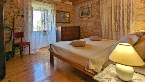 A bedroom with a wooden bed, a nightstand, a chair, and a window with curtains.