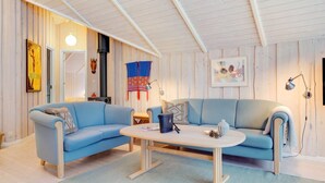 Una habitación acogedora con un sofá azul, una mesita y una chimenea.