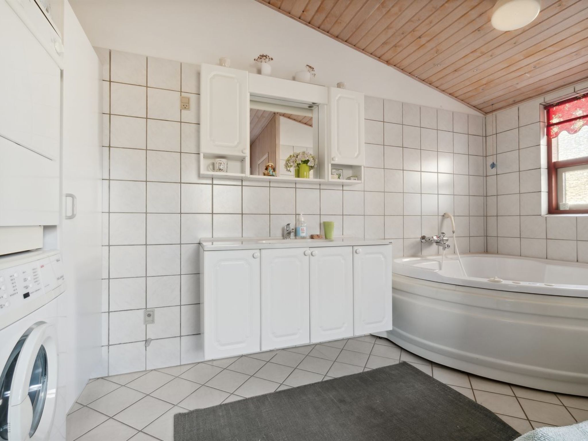 A modern bathroom with a washing machine, a sink, a mirror, and a bathtub.
