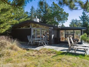 Enjoy al fresco dining on the spacious deck surrounded by lush greenery and tall trees.
