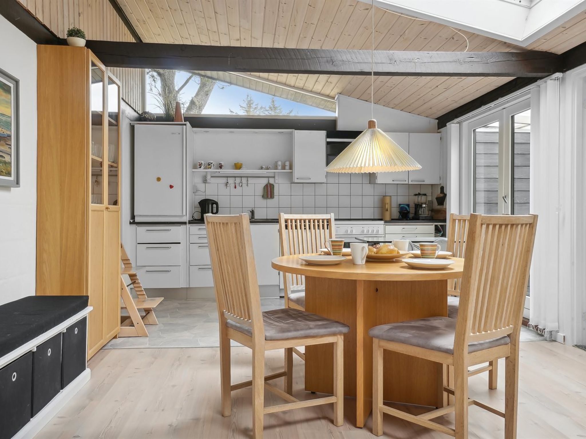 Una cocina moderna con armarios blancos, una mesa de comedor de madera y sillas.